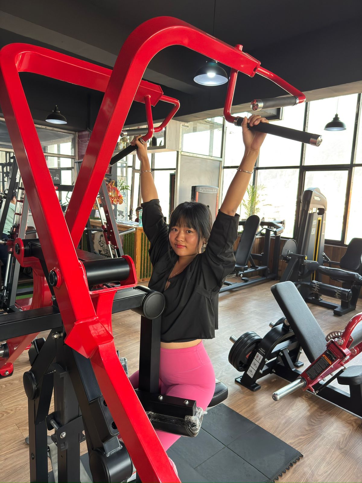 Female member training on lat pulldown machine at Muscle Mania Fitness Club